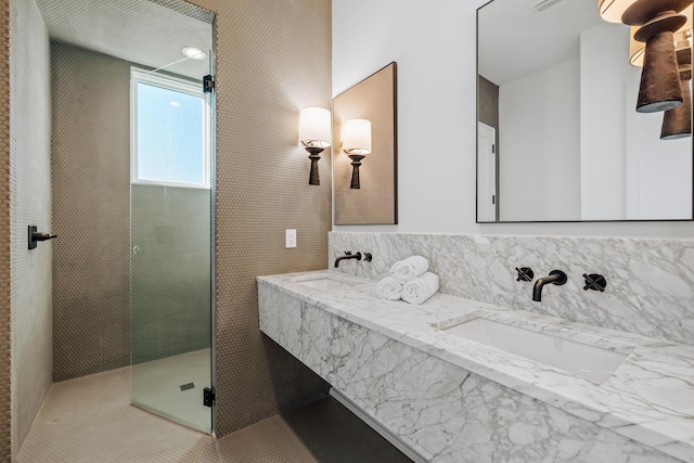 full bath featuring a tile shower, double vanity, and a sink