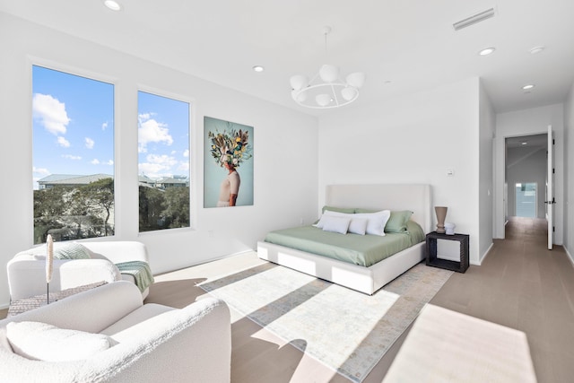 bedroom with a notable chandelier, visible vents, wood finished floors, and recessed lighting