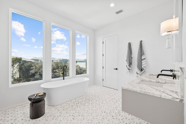 full bath featuring a freestanding tub, recessed lighting, a sink, visible vents, and double vanity