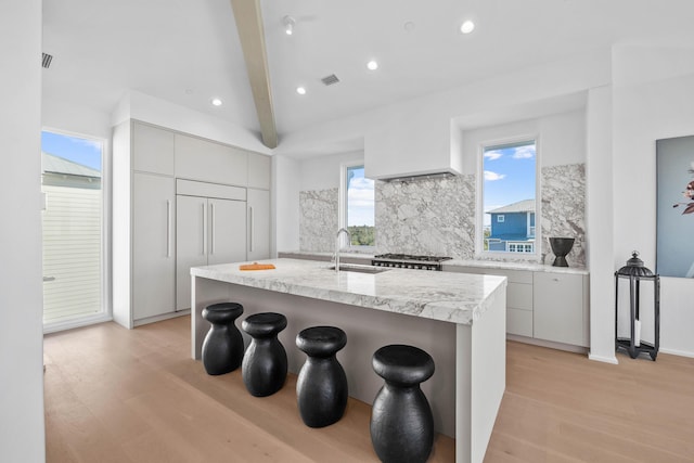 kitchen with light wood-type flooring, a breakfast bar, modern cabinets, and a sink