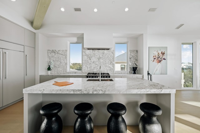 kitchen with tasteful backsplash, modern cabinets, visible vents, and a kitchen breakfast bar