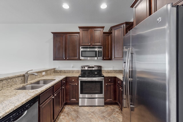 8872 White Ibis Way, Navarre, FL 32566 - kitchen with dark brown cabinetry, recessed lighting, light stone counters, a sink, and appliances with stainless steel finishes