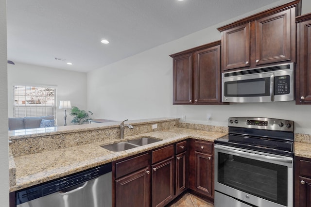 8872 White Ibis Way, Navarre, FL 32566 - kitchen featuring visible vents, dark brown cabinets, light stone countertops, a sink, and stainless steel appliances