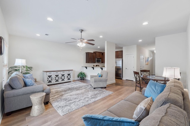 living room featuring ceiling fan and light hardwood / wood-style floors