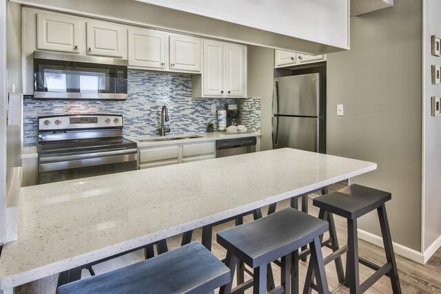500 Gulf Shore Dr Unit 115B, Destin, FL 32541 - kitchen featuring appliances with stainless steel finishes, wood-type flooring, sink, a breakfast bar area, and backsplash