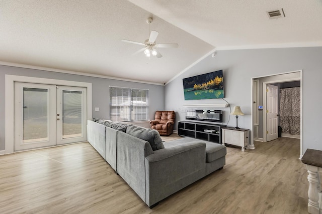 living room with lofted ceiling, ceiling fan, light hardwood / wood-style flooring, and a textured ceiling