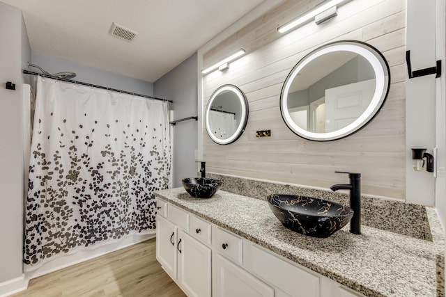 bathroom with wood walls, wood-type flooring, vanity, and a shower with curtain