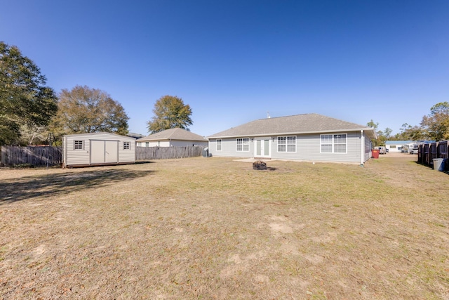 back of house featuring an outdoor fire pit, a yard, and a shed