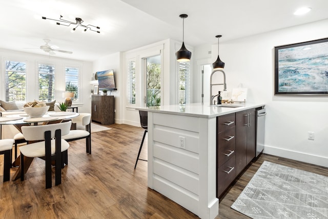 kitchen with sink, decorative light fixtures, dark brown cabinets, dark hardwood / wood-style flooring, and kitchen peninsula