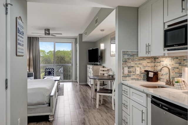 kitchen with white cabinetry, sink, decorative backsplash, stainless steel appliances, and light stone countertops