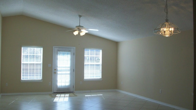 tiled spare room featuring lofted ceiling, ceiling fan with notable chandelier, and a textured ceiling