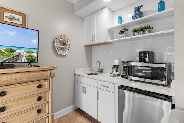 kitchen with refrigerator, sink, white cabinets, decorative backsplash, and light stone countertops