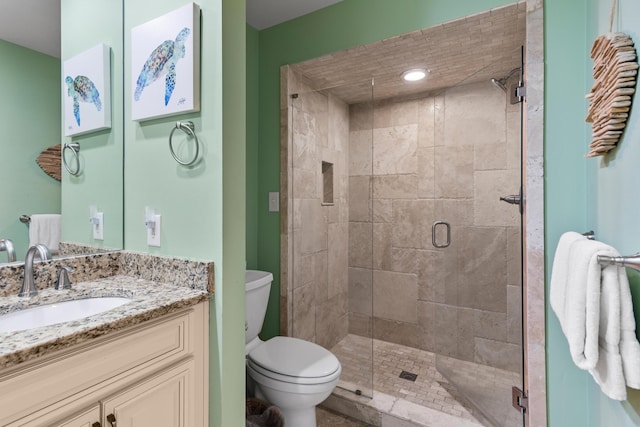 bathroom featuring vanity, toilet, and a shower with shower door