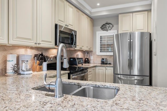 kitchen featuring light stone counters, appliances with stainless steel finishes, and cream cabinetry