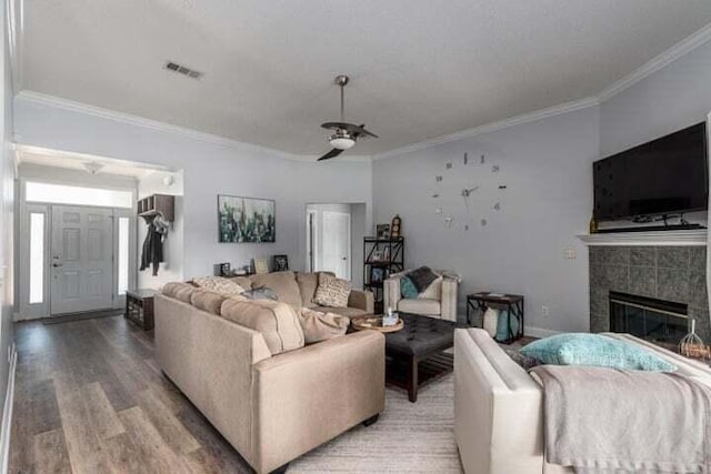 living room featuring crown molding, ceiling fan, hardwood / wood-style floors, and a tile fireplace