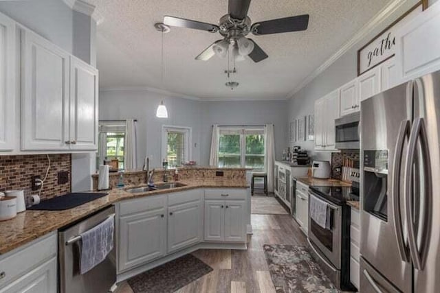 kitchen featuring sink, stainless steel appliances, kitchen peninsula, and white cabinets