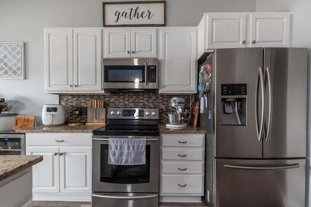 kitchen with stainless steel appliances, light stone counters, tasteful backsplash, white cabinets, and beverage cooler