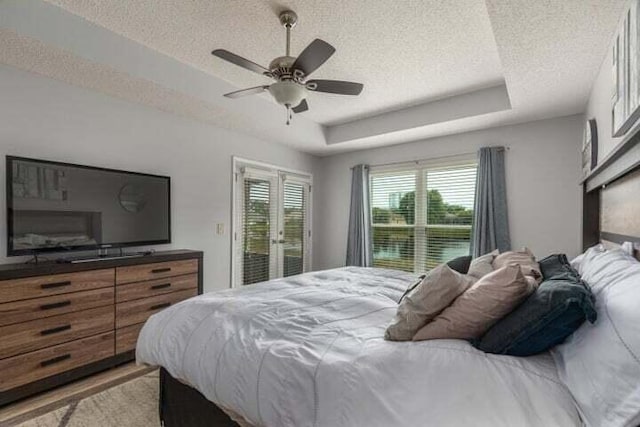 bedroom featuring ceiling fan, a tray ceiling, and a textured ceiling