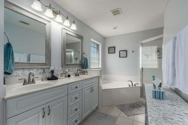 bathroom featuring independent shower and bath, vanity, tile patterned flooring, and a textured ceiling