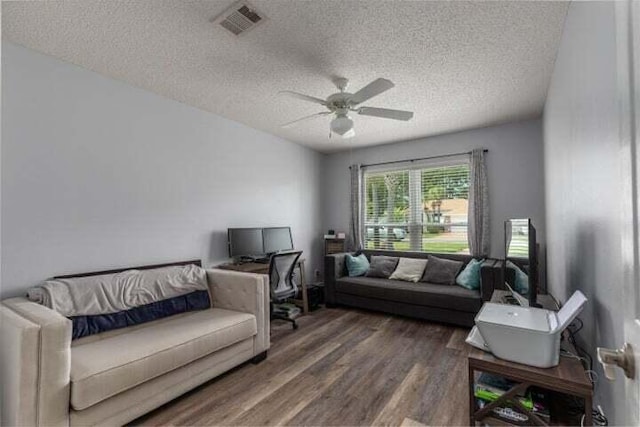 living room featuring dark wood-type flooring, a textured ceiling, and ceiling fan