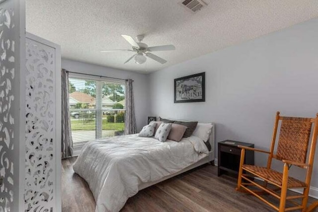 bedroom with ceiling fan, dark wood-type flooring, and a textured ceiling