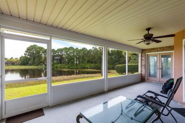 unfurnished sunroom with a water view and ceiling fan