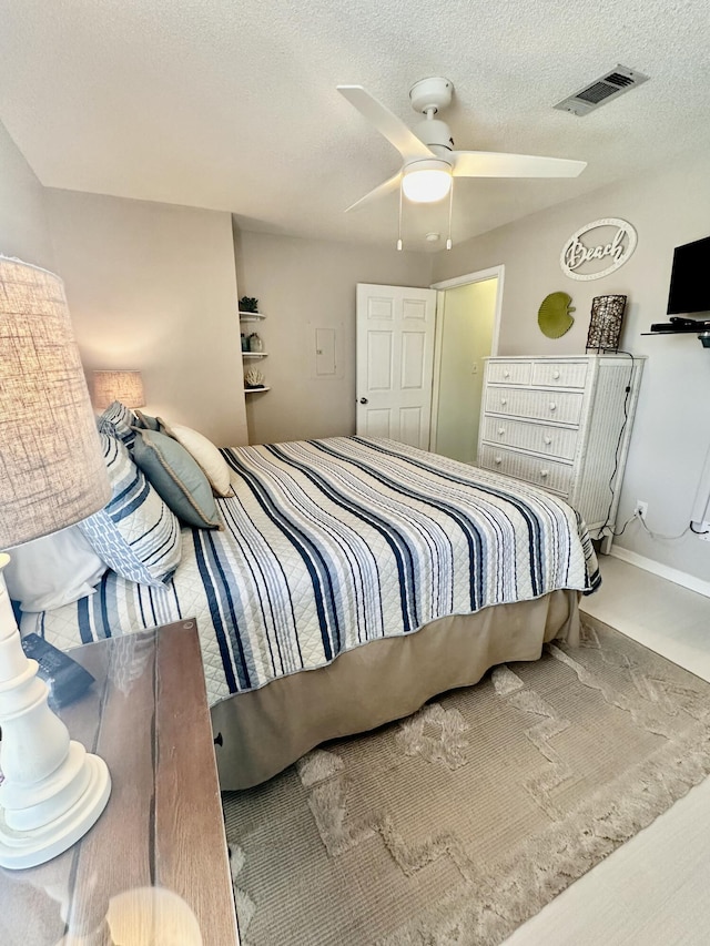 bedroom with ceiling fan and a textured ceiling