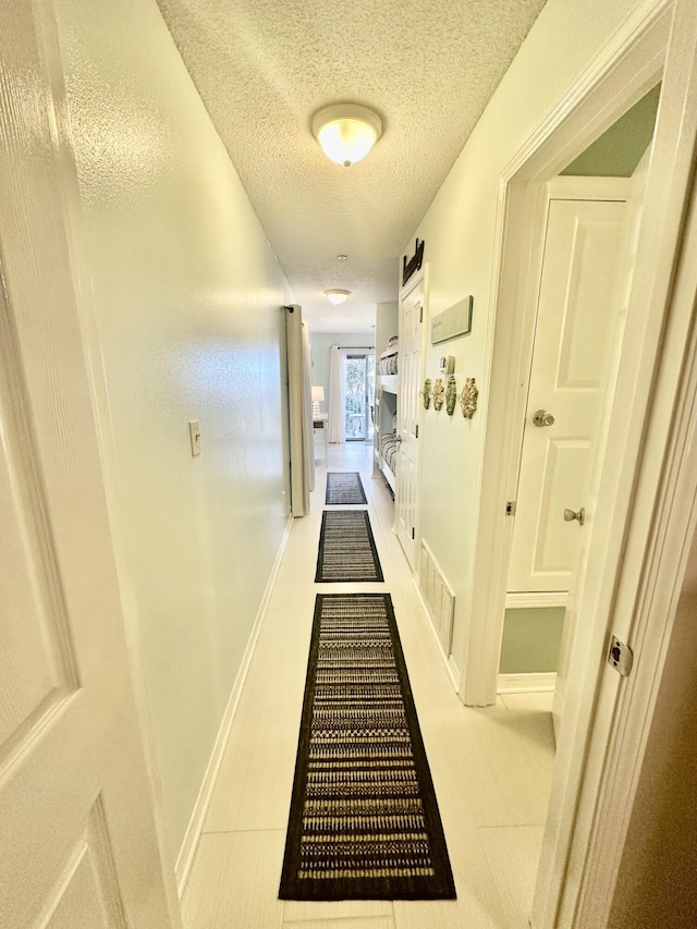 hallway featuring light tile patterned floors and a textured ceiling