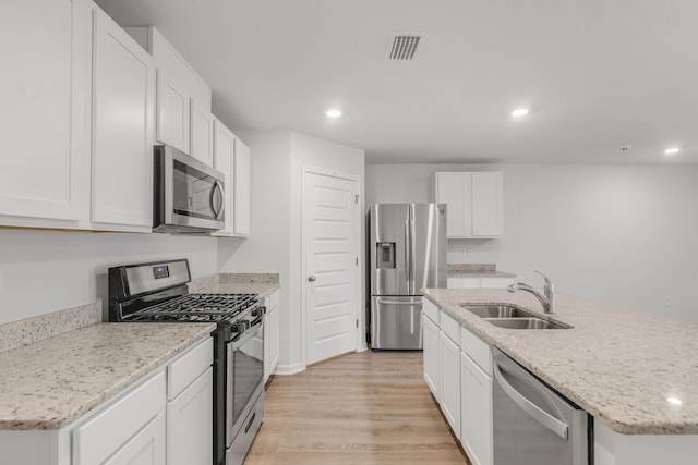 kitchen with sink, light hardwood / wood-style flooring, a center island with sink, stainless steel appliances, and white cabinets