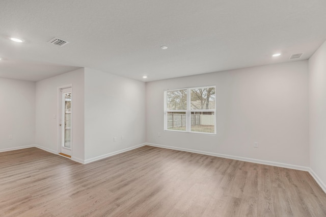 unfurnished room featuring a textured ceiling and light hardwood / wood-style floors