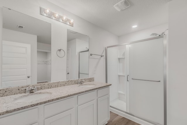 bathroom with walk in shower, vanity, a textured ceiling, and hardwood / wood-style flooring