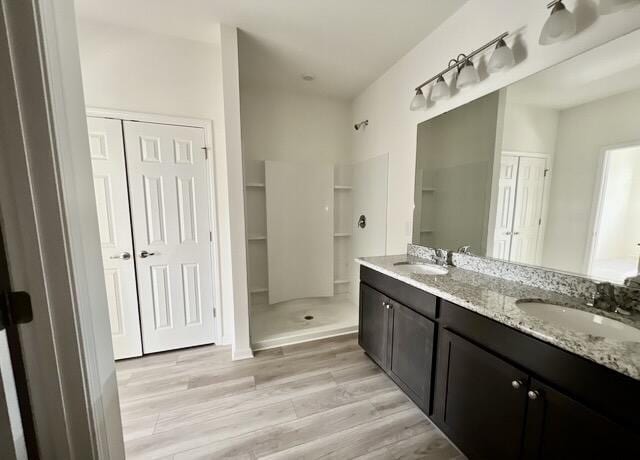 bathroom featuring hardwood / wood-style flooring, a shower, and vanity