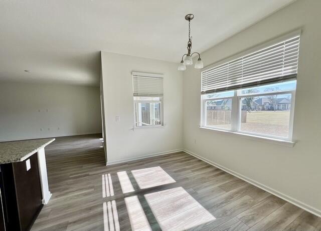 unfurnished dining area featuring hardwood / wood-style flooring and an inviting chandelier