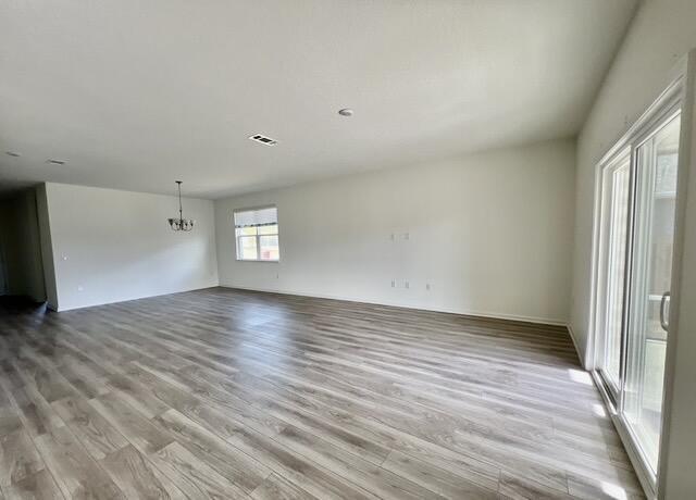 empty room with an inviting chandelier and light wood-type flooring