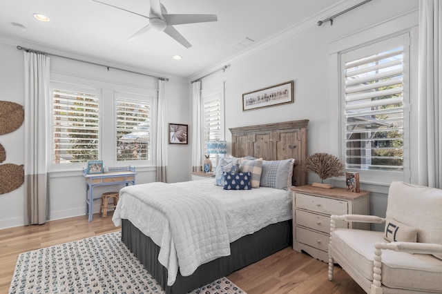 bedroom featuring crown molding, ceiling fan, wood-type flooring, and multiple windows