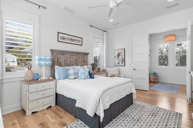 bedroom with multiple windows, ornamental molding, ceiling fan, and light wood-type flooring