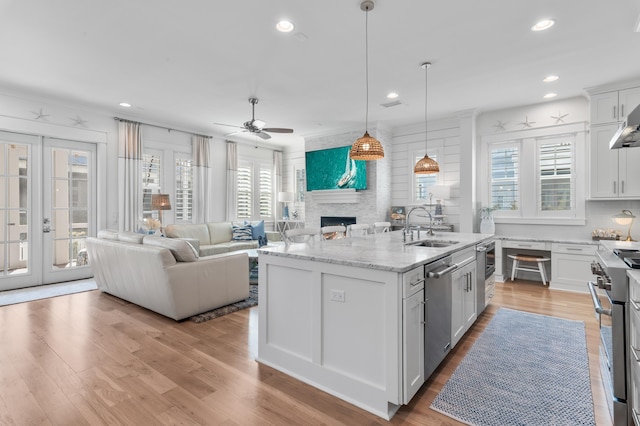 kitchen with sink, stainless steel appliances, white cabinets, and a center island with sink