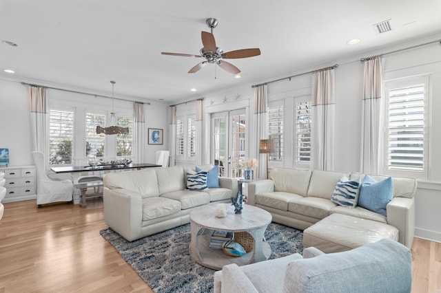 living room with light hardwood / wood-style flooring, ornamental molding, and ceiling fan