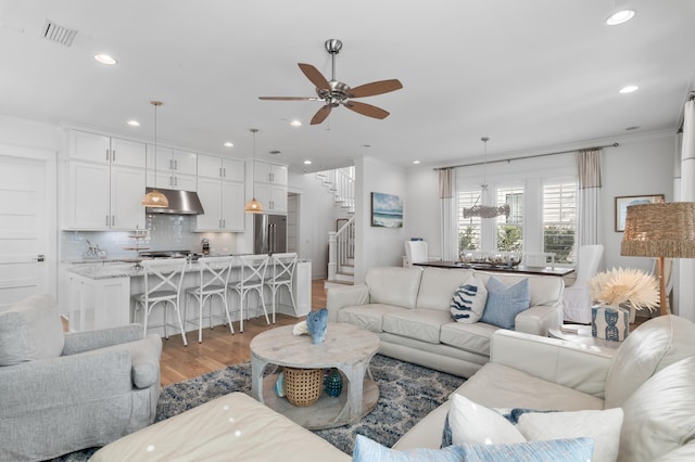 living room with ornamental molding, ceiling fan, and light hardwood / wood-style flooring