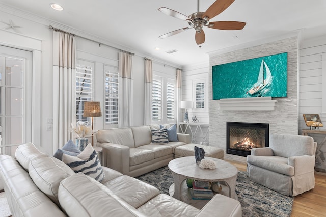 living room with crown molding, ceiling fan, a fireplace, and light hardwood / wood-style flooring