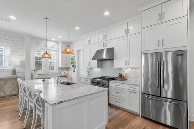 kitchen with high end appliances, sink, a kitchen island with sink, and white cabinets