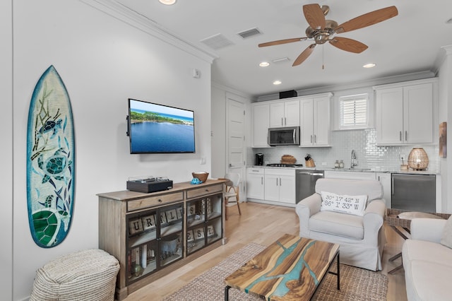 living room with ceiling fan, ornamental molding, light hardwood / wood-style floors, and sink