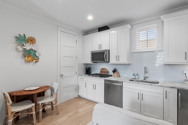 kitchen featuring stainless steel appliances, white cabinetry, sink, and light stone counters