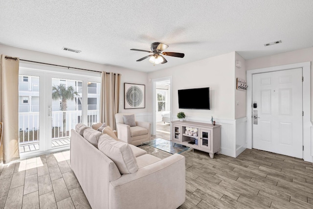 living room featuring ceiling fan and a textured ceiling