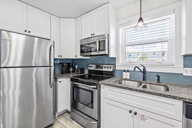 kitchen featuring sink, white cabinetry, tasteful backsplash, dark stone countertops, and appliances with stainless steel finishes