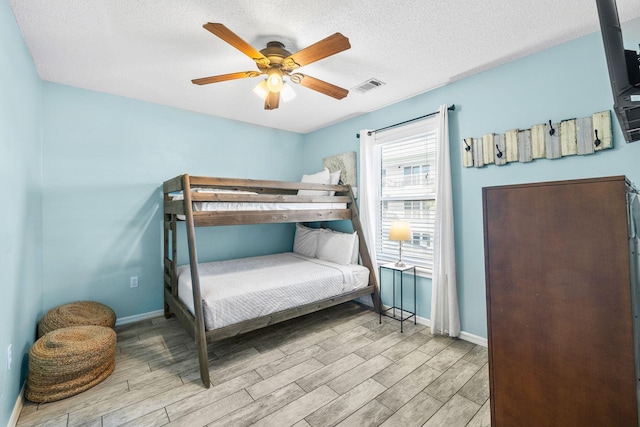 bedroom featuring ceiling fan, light hardwood / wood-style flooring, and a textured ceiling