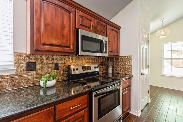 kitchen with lofted ceiling, tasteful backsplash, dark stone counters, dark hardwood / wood-style flooring, and stainless steel appliances