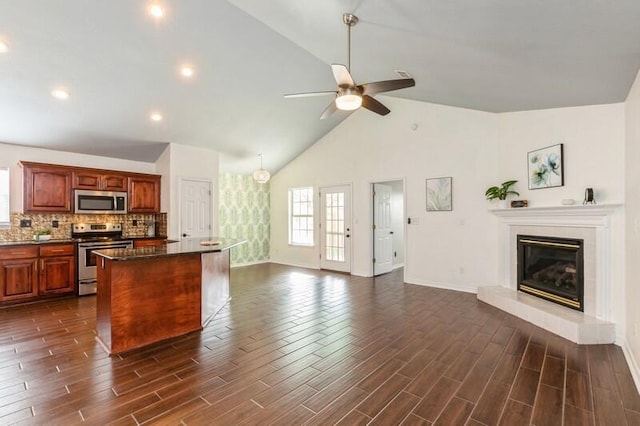 kitchen with appliances with stainless steel finishes, a center island, dark wood-type flooring, and a fireplace