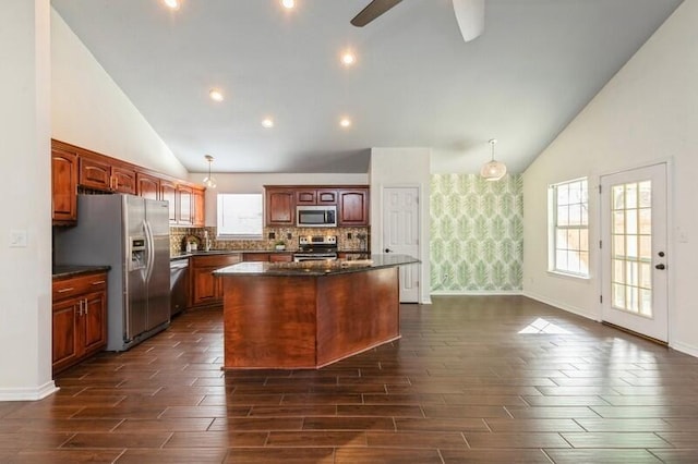 kitchen featuring a kitchen island, appliances with stainless steel finishes, backsplash, hanging light fixtures, and ceiling fan