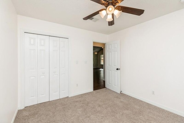 unfurnished bedroom with ceiling fan, light colored carpet, and a closet